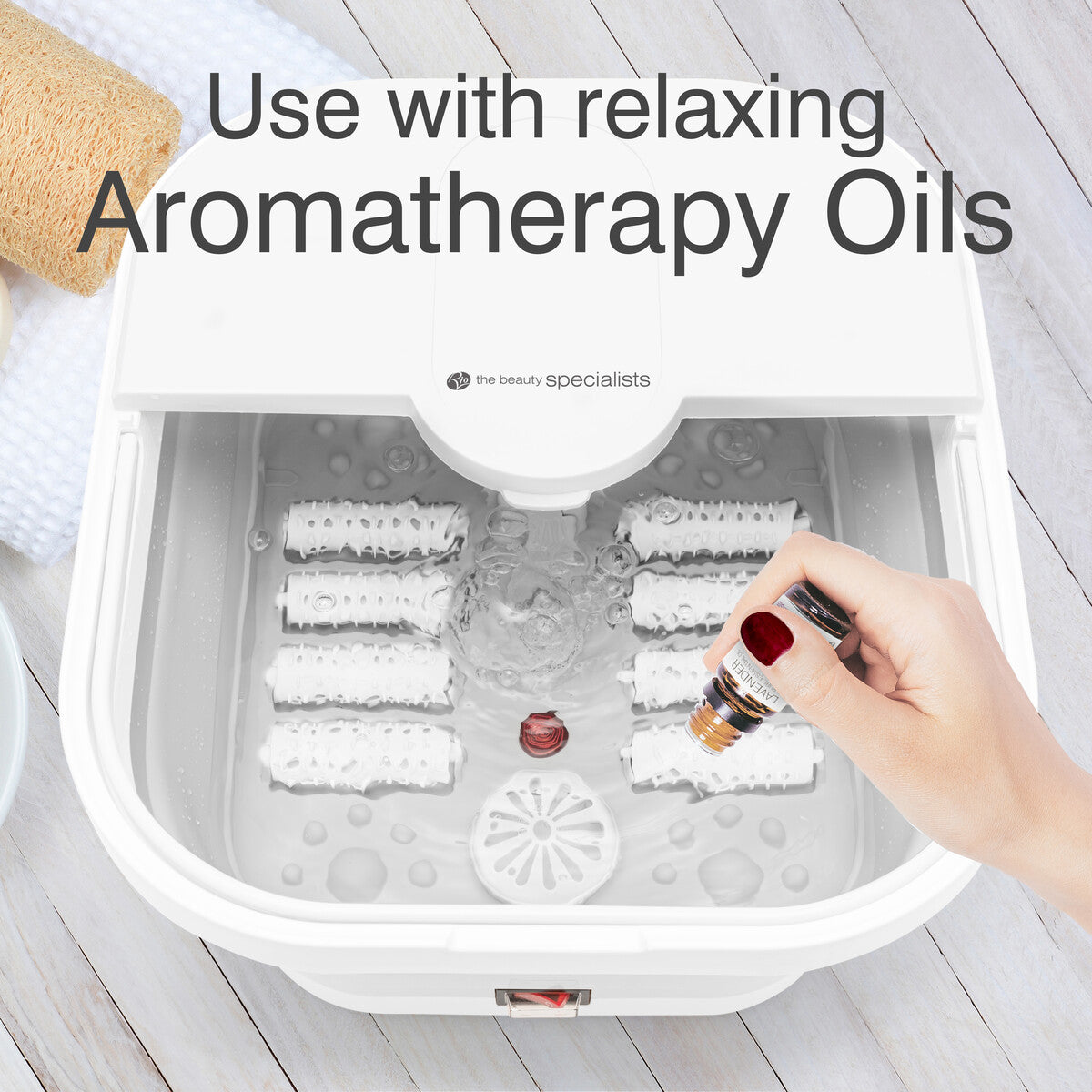 A hand pouring aromatherapy oils into the Foldaway Foot Spa Bath to enhance relaxation. The text promotes the use of "Aromatherapy Oils," making this foot spa machine one of the best foot spa options for combining massage, heat, and aromatherapy in a foot soaker.