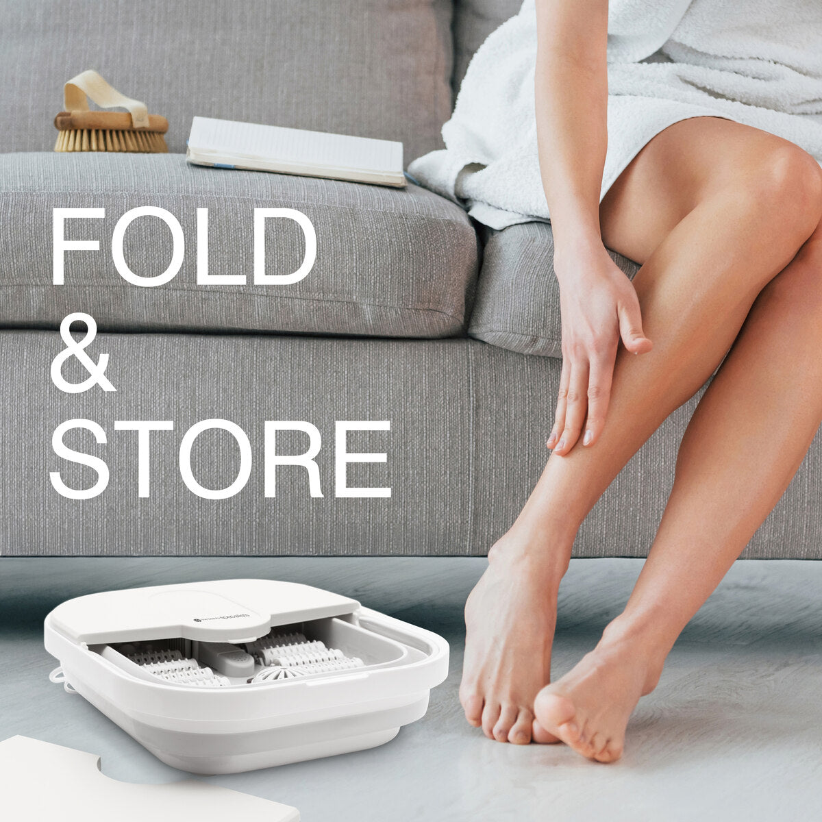 A lifestyle image showing the Foldaway Foot Spa Bath neatly folded and stored under a sofa, with the text "FOLD & STORE." This compact design makes this footbath one of the most convenient foot spa machines for home use, combining ease of storage with therapeutic features.