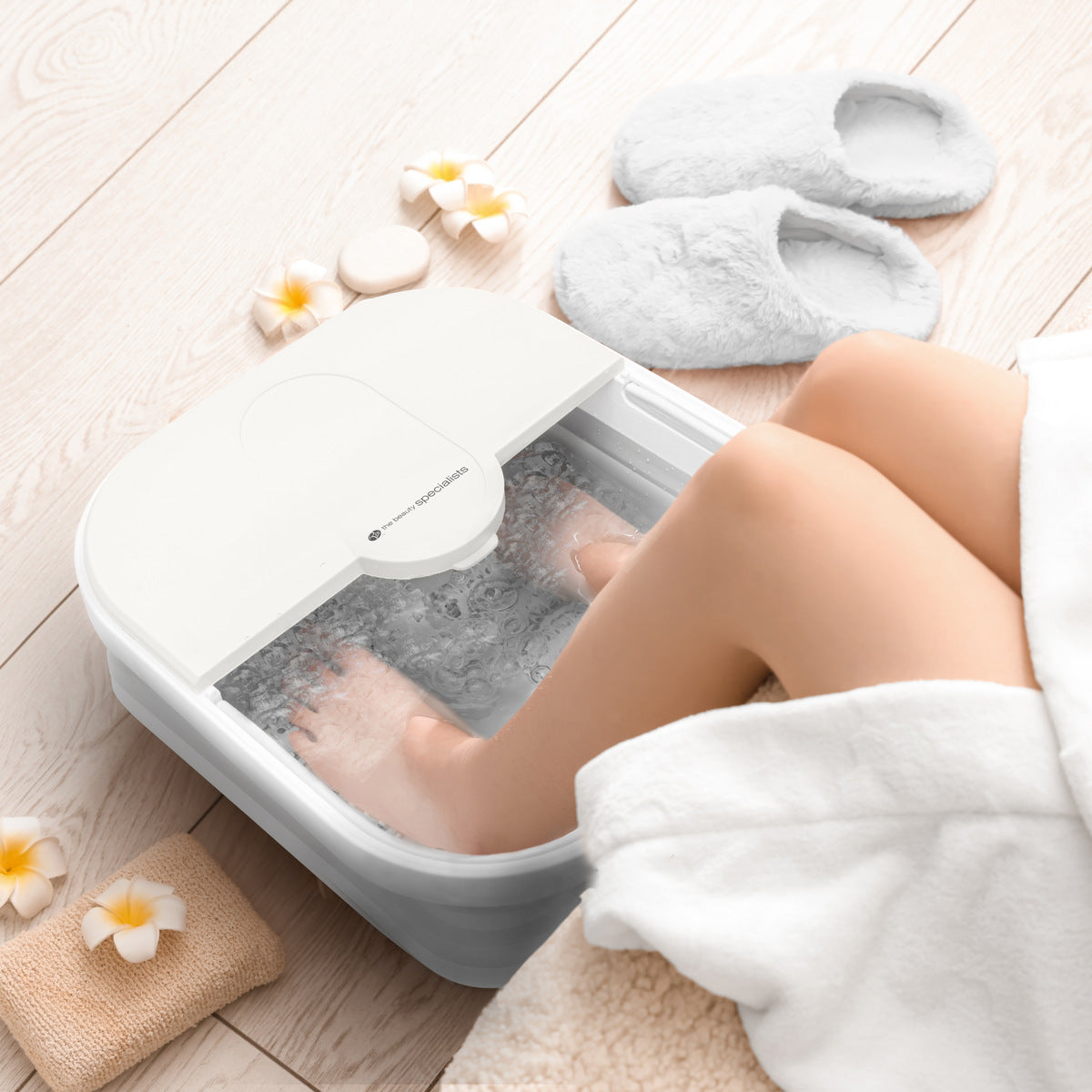 A relaxing scene showing a person's feet submerged in the Foldaway Foot Spa Bath, enjoying a soothing soak. The text reads "A Relaxing Moment of Indulgence," emphasizing the calming experience provided by this foot spa machine for a home foot massage spa.