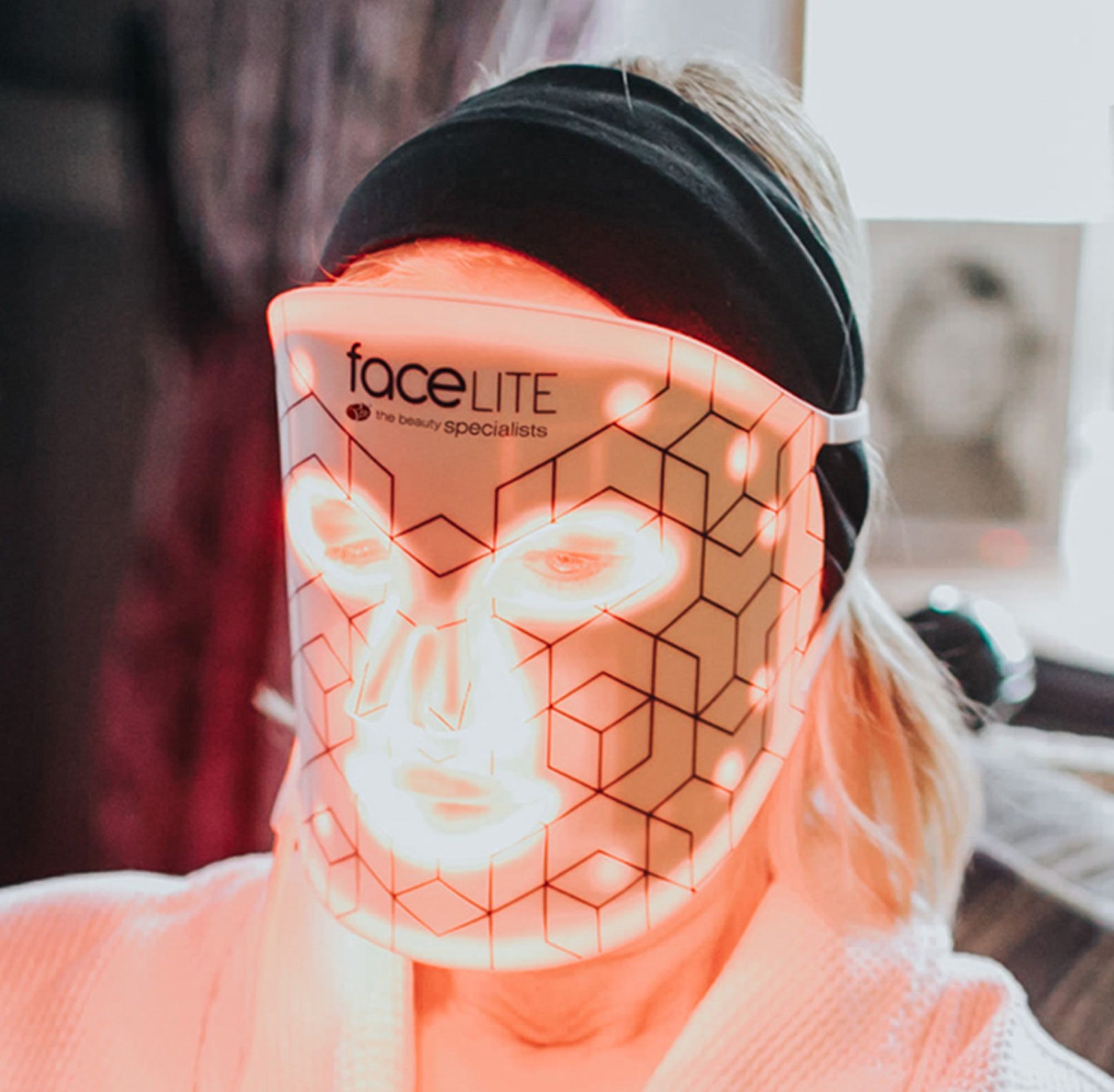 blonde lady relaxing wearing facelite beauty boosting LED face mask with red and infrared lights illuminated 