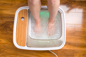birdseye view of Scandinavian jacuzzi foot spa with feet inside, green spa lights illuminated and filled with bubbling water