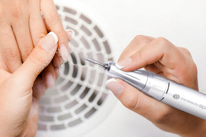 Professional electric nail file being used in salon to file down acrylic manicure