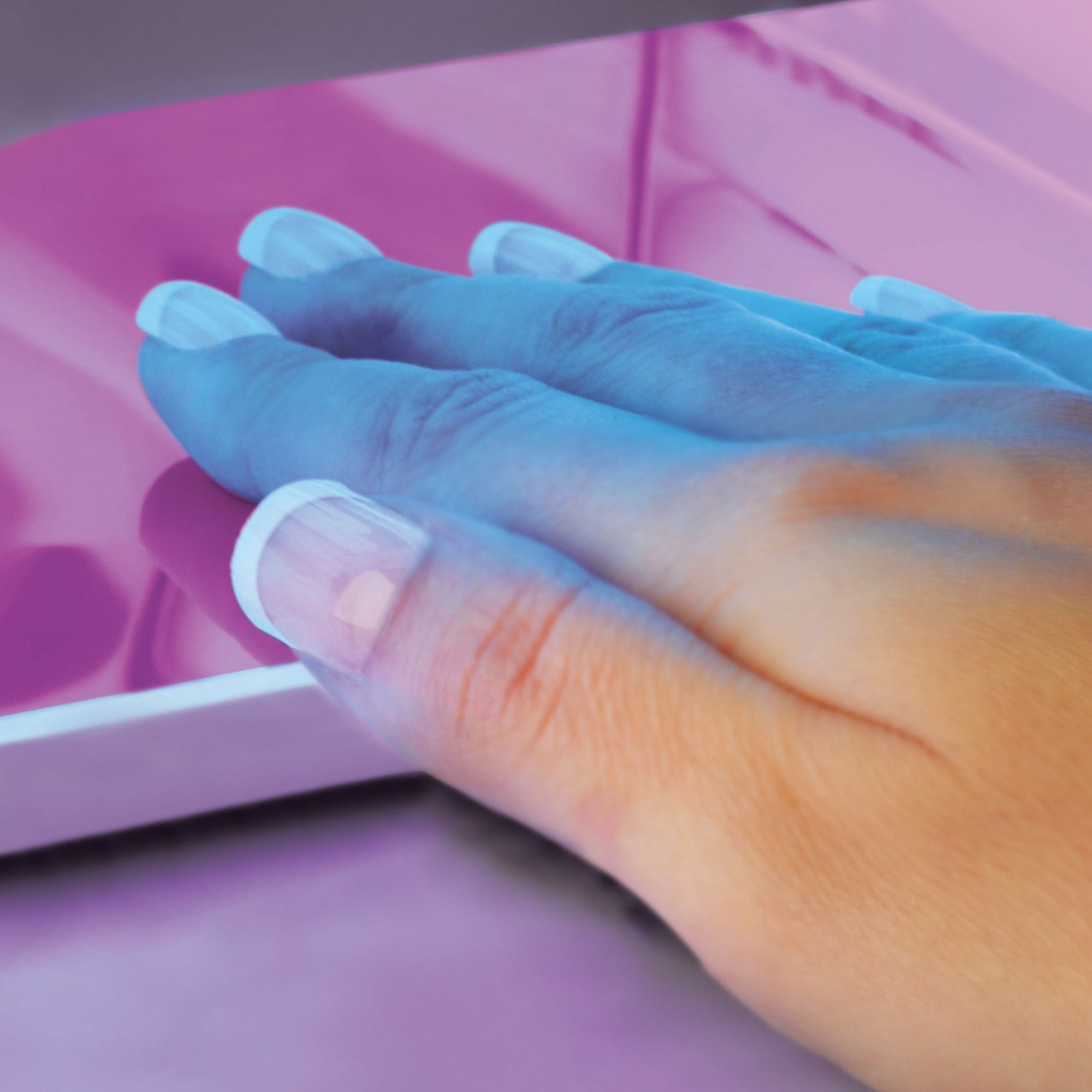 ladies hand under UV nail lamp curing gel nail extensions