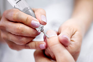 professional electric nail file being used to file thumb nails