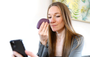 lady using pore perfector wireless purple unit  on face while looking and smartphone 