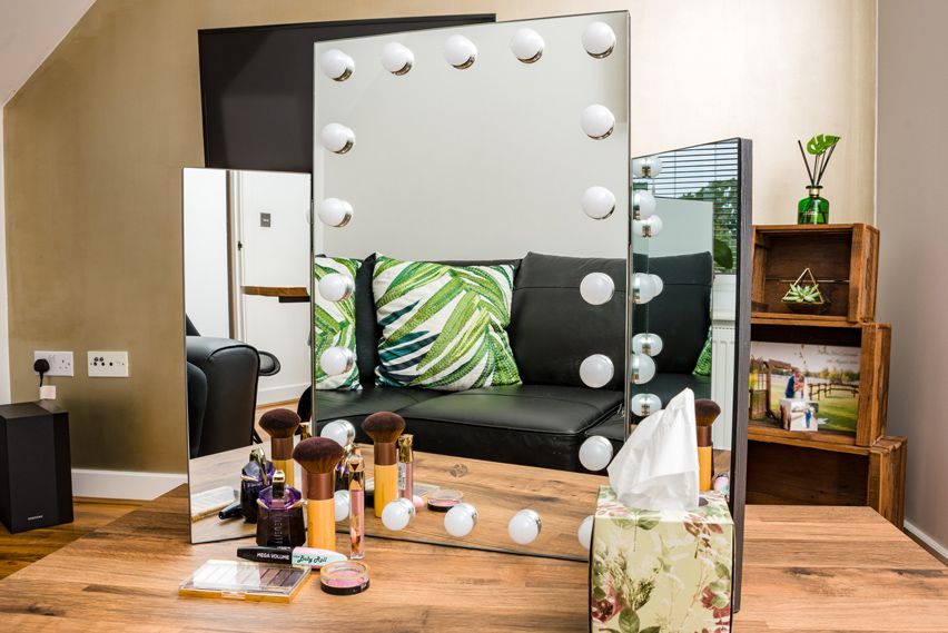 premier hollywood mirror with 20 LED lights and folding side mirrors stood on dressing table surrounded by cosmetics